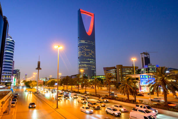 ww Multiple lane traffic travelling past landmark Centrepoint Tower with upside down parabolic arch illuminated in red against twilight sky.